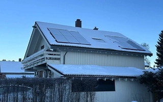 Bilde av snødekt, hvitt hus med solceller på taket