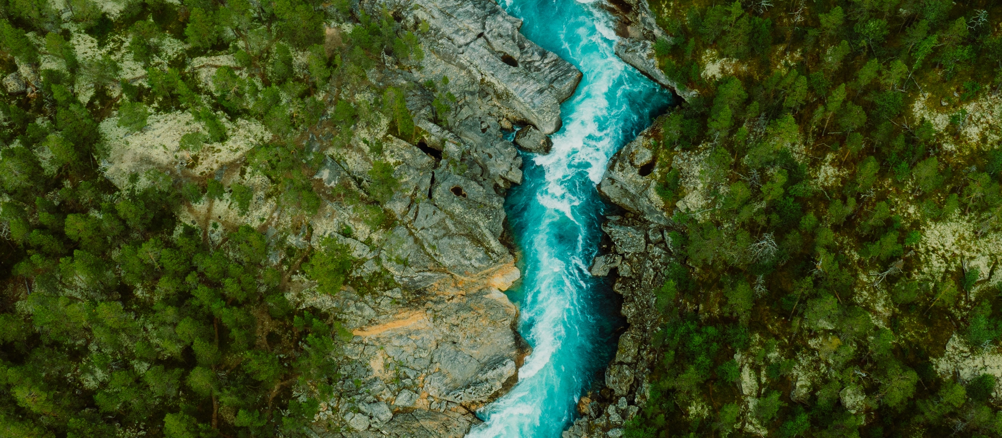 Istock: Drone bilde av turkisfarget elv som renner gjennom grønn skog. 