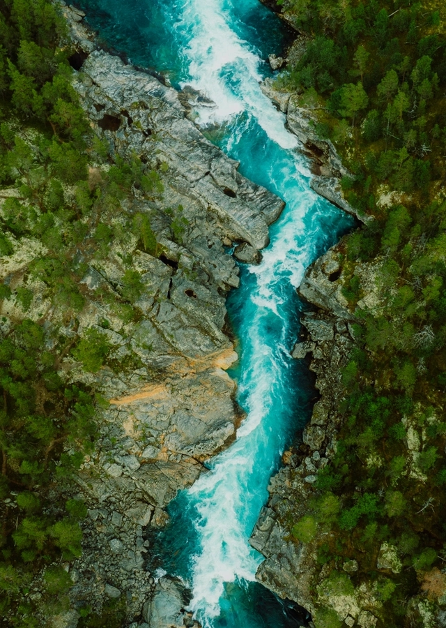 Istock: Drone bilde av turkisfarget elv som renner gjennom grønn skog. 